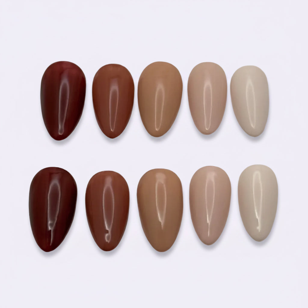 Nine almond-shaped false nail tips arranged in two rows on a light gray background, showing a gradient of colors from deep burgundy and warm brown to light beige and nude.