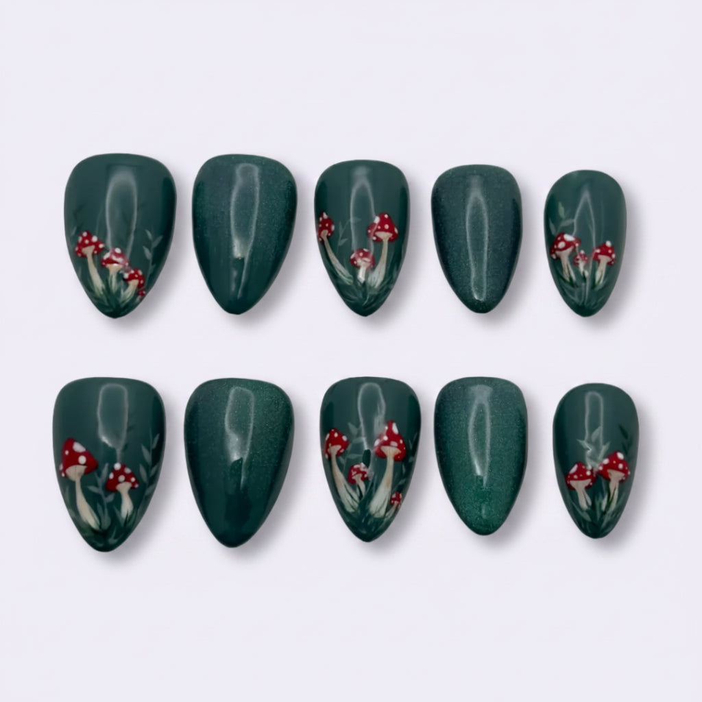 A set of ten press-on nails arranged in two rows of five on a light gray background. The nails are a deep forest green with a glossy finish and decorated with small red berries and white leafy stems.