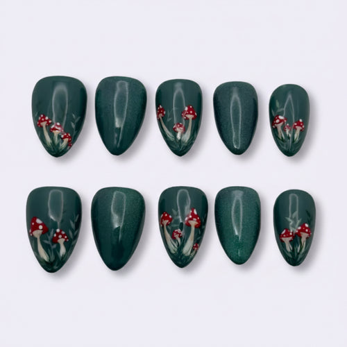 A set of ten press-on nails arranged in two rows of five on a light gray background. The nails are a deep forest green with a glossy finish and decorated with small red berries and white leafy stems.